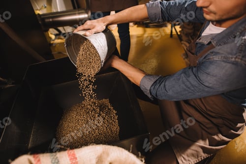 Preview: partial view of coffee roaster pouring coffee beans into roasting machine