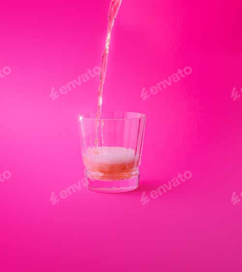 Preview: Pink drink being poured into a glass on a pink background