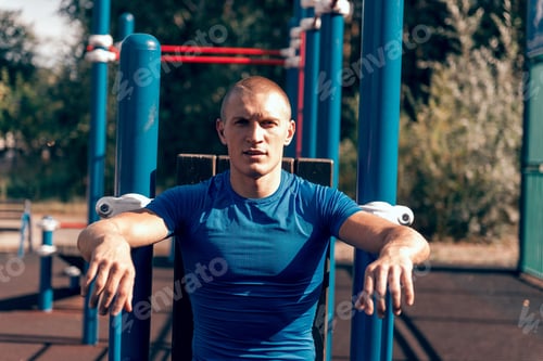 Preview: strong trained man posing on the sports field, look at camera