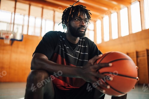 Preview: African american basketball player holding a ball on court on training.