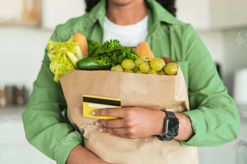 Preview: African woman holding credit card and grocery shopping bag indoor