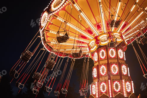 Preview: Illuminated swing chain carousel in amusement park at the night