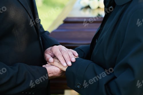 Preview: Close-up of hands of mature grieving man on those of his mourning wife