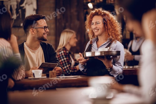 Preview: Happy waitress talking to guests while serving them in a cafe.
