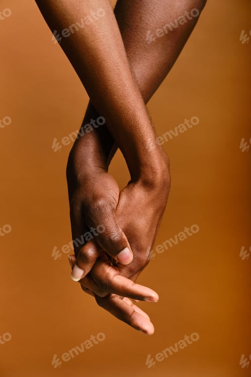 Preview: Black young adult couple holding hands representing connection. unrecognizable person