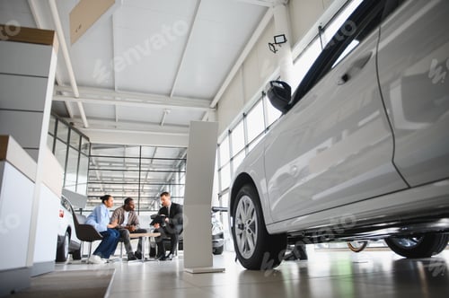 Preview: African american Couple choosing new car with salesman in dealership