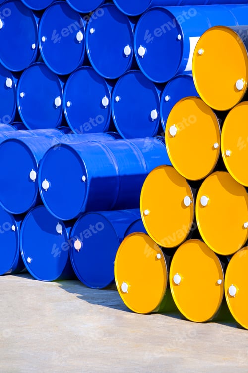 Preview: Stack of many yellow and blue 200 liter oil drums in industrial yard area