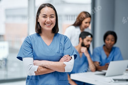 Preview: Portrait of a doctor standing in a hospital with her colleagues in the background