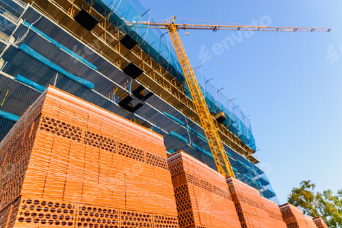 Preview: Yellow crane on a construction site to lift large weights of construction material.