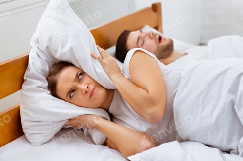 Preview: Angry Girlfriend Covering Ears Lying Near Snoring Boyfriend In Bed