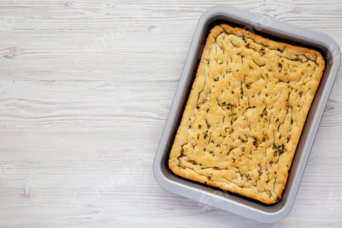 Preview: Home-baked Rosemary Garlic Focaccia Bread on baking tray, top view.