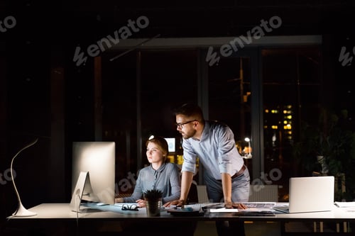 Preview: Businesspeople in the office at night working late.