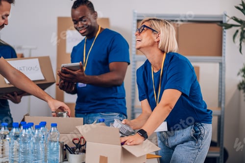 Preview: Diverse volunteers working in a charity donation center and packing clothes and food