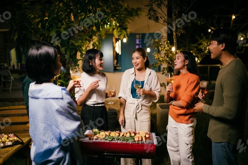 Preview: Friends enjoying barbecue and drinks at night party in the backyard