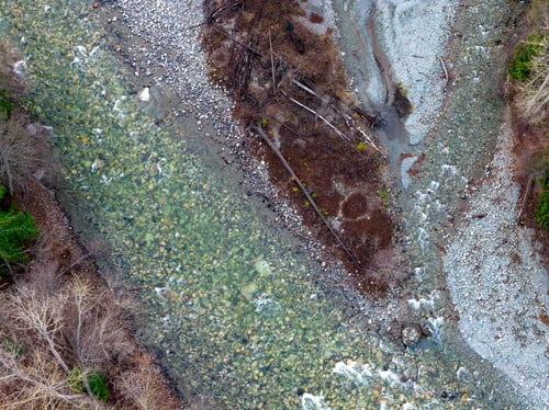 Preview: Aerial View Of Clear River, Rocky Shore, And Fallen Trees In BC Landscape