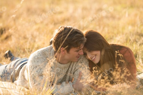 Preview: Young couple lying in field, smiling