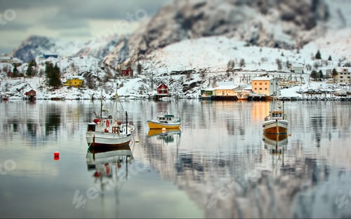 Preview: Landscape of boats on the sea surrounded by rocky mountains covered in the snow in Lofoten, Norway