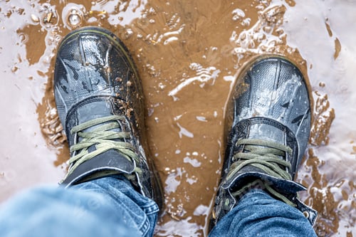 Preview: View from above on pair of trekking shoes in a mud.