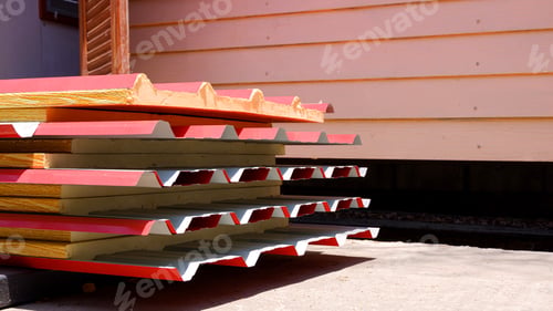 Preview: Red corrugated metal roof with PU foam insulation stacked on the ground in house construction site