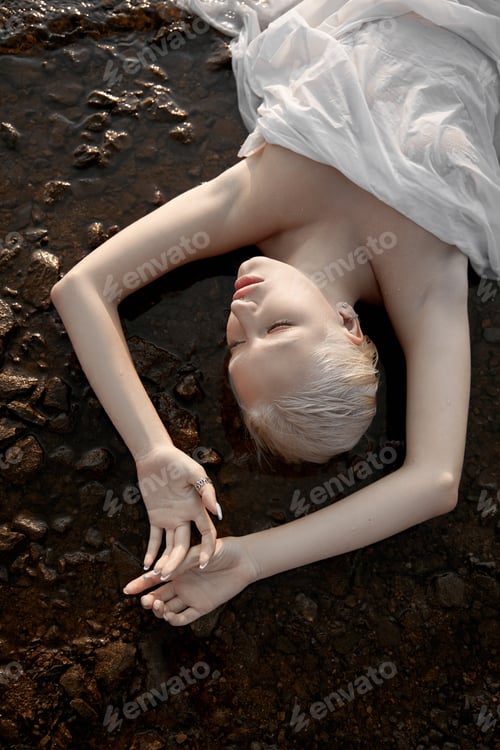 Preview: Beautiful blonde woman short hair lies water sea shore, pond. Art portrait relaxing woman in water