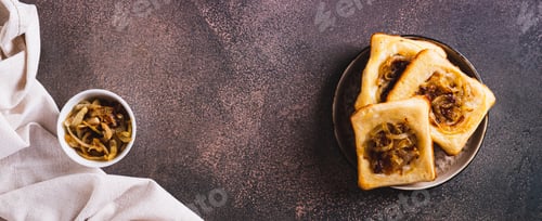 Preview: Homemade caramelized onion upside down pies on a plate on a table top view web banner