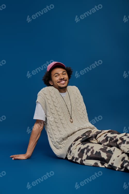 Preview: Young man with vibrant style smiles warmly against a striking blue backdrop
