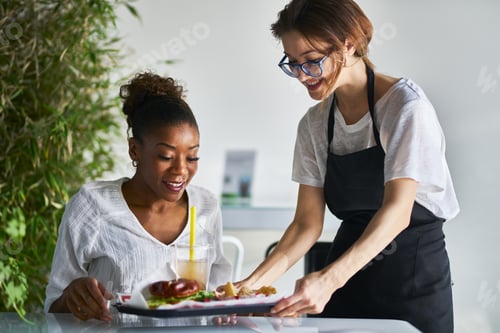 Preview: african american women being served tray of healthy vegan food at restaurant