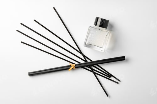 Preview: A minimalist display of essential oil and black diffuser sticks on a clean white background