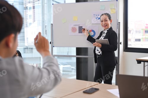 Preview: Confident business woman team leader standing near flip chart with graphs diagrams.