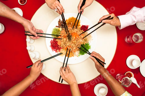 Preview: Hands holding chopsticks ready to toss Yee Sang dish into the air