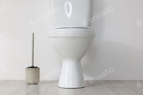 Preview: Toilet and brush on floor near white wall