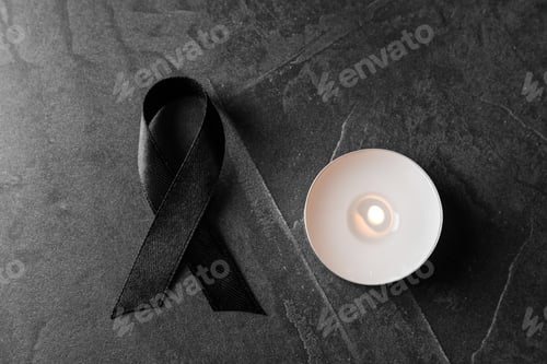 Preview: Black ribbon and burning candle on dark grey stone surface, top view. Funeral symbols