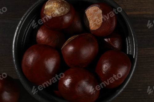 Preview: Brown chestnut fruits in a black bowl on a dark background