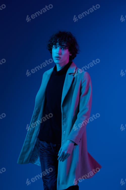Preview: Man in fashion coat on dark blue background, neon light, style and trends, mixed light, men's