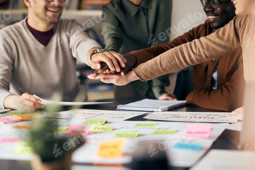 Preview: Close up of creative business team gathering hands in unity while working in the office.