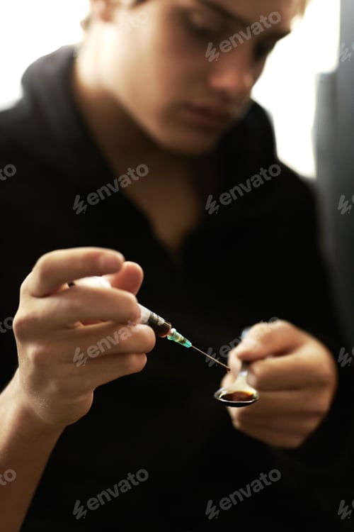 Preview: Down a dark path. Shot of a young man preparing a shot of heroin.