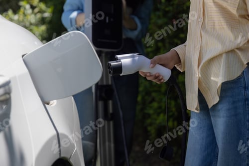 Preview: Teenage Girls EV charging an electric car.