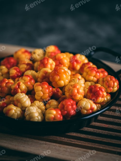 Preview: Vertical shot of a black pan full of cloudberries