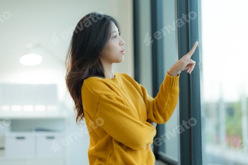 Preview: Thoughtful young woman looking out window