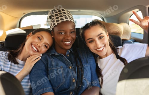 Preview: Cheerful multiracial girlfriends riding car together, smiling at camera