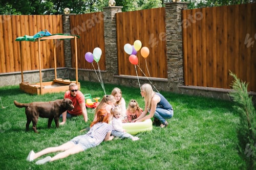 Preview: young family girl and guy with small children walking on green grass in the yard of the house