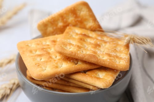 Preview: Tasty salty crackers with wheat spikes on white table, closeup