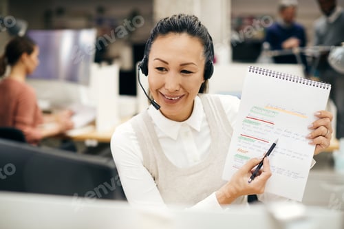 Preview: Happy Asian businesswoman going through summary of a report during conference call in the office.
