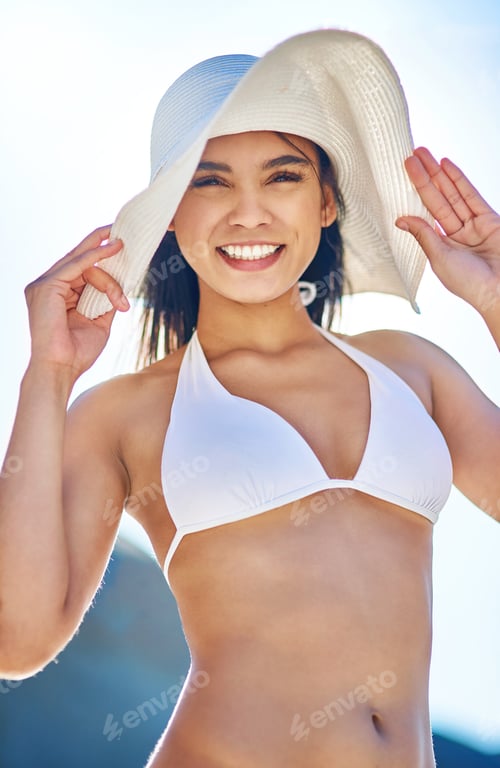 Preview: Portrait of a beautiful young woman in a white bikini posing on the beach