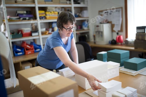 Preview: Female worker packing stacked paper in printing press workshop