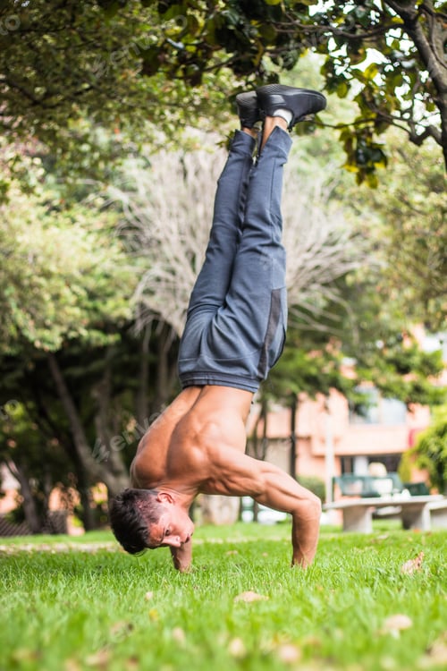 Preview: Hot attractive man doing a handstand on green grass