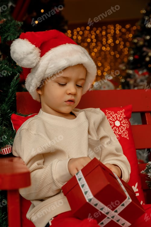 Preview: A child opens a new year gift box with surprise, wearing Santa Clause hat