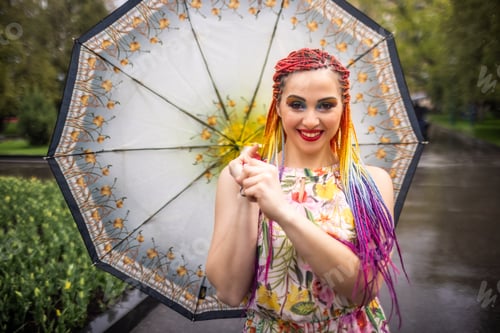 Preview: A pretty girl in a beautiful dress with bright multi-colored braids and shiny makeup is whirling in