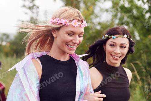 Preview: Two Excited Young Female Friends Arriving At Music Festival Walking Through Field