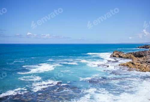 Preview: Serene coastal landscape with turquoise waters gently lapping against rocky shore